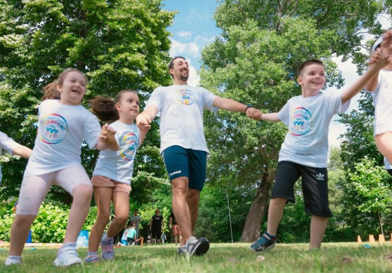 Group of joyful children playing outdoors with an instructor in a sunny park.